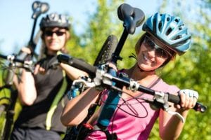 Sporty couple carrying their mountain bikes